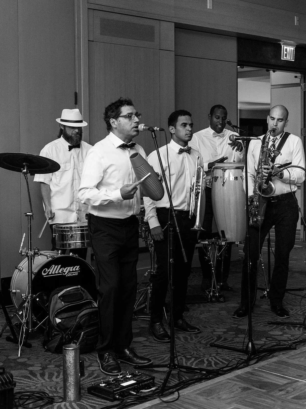 Live wedding band performing with percussion, saxophone and vocals during the reception.