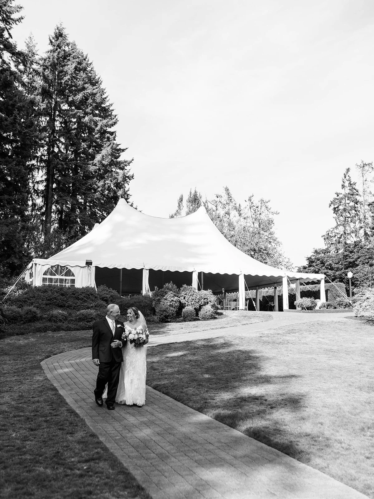 Bride walking with her father toward outdoor garden ceremony at Abernathy Center.