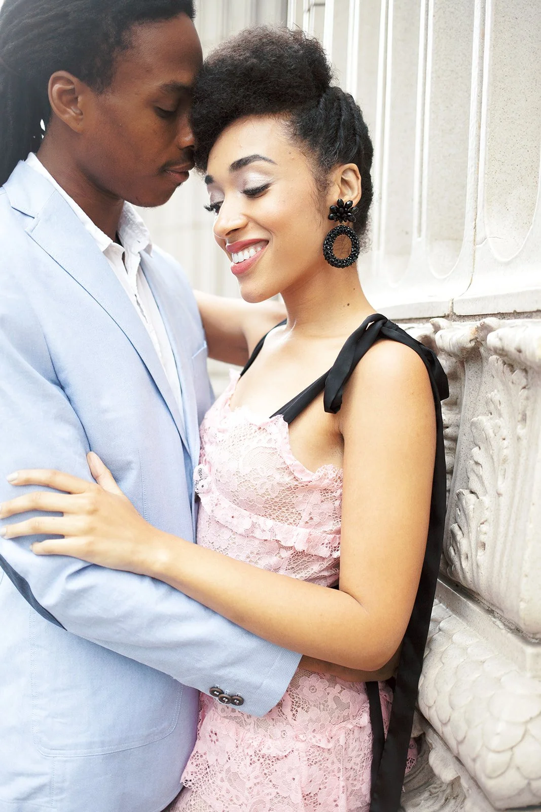 Close-up of couple embracing beside ornate Portland building, soft natural light