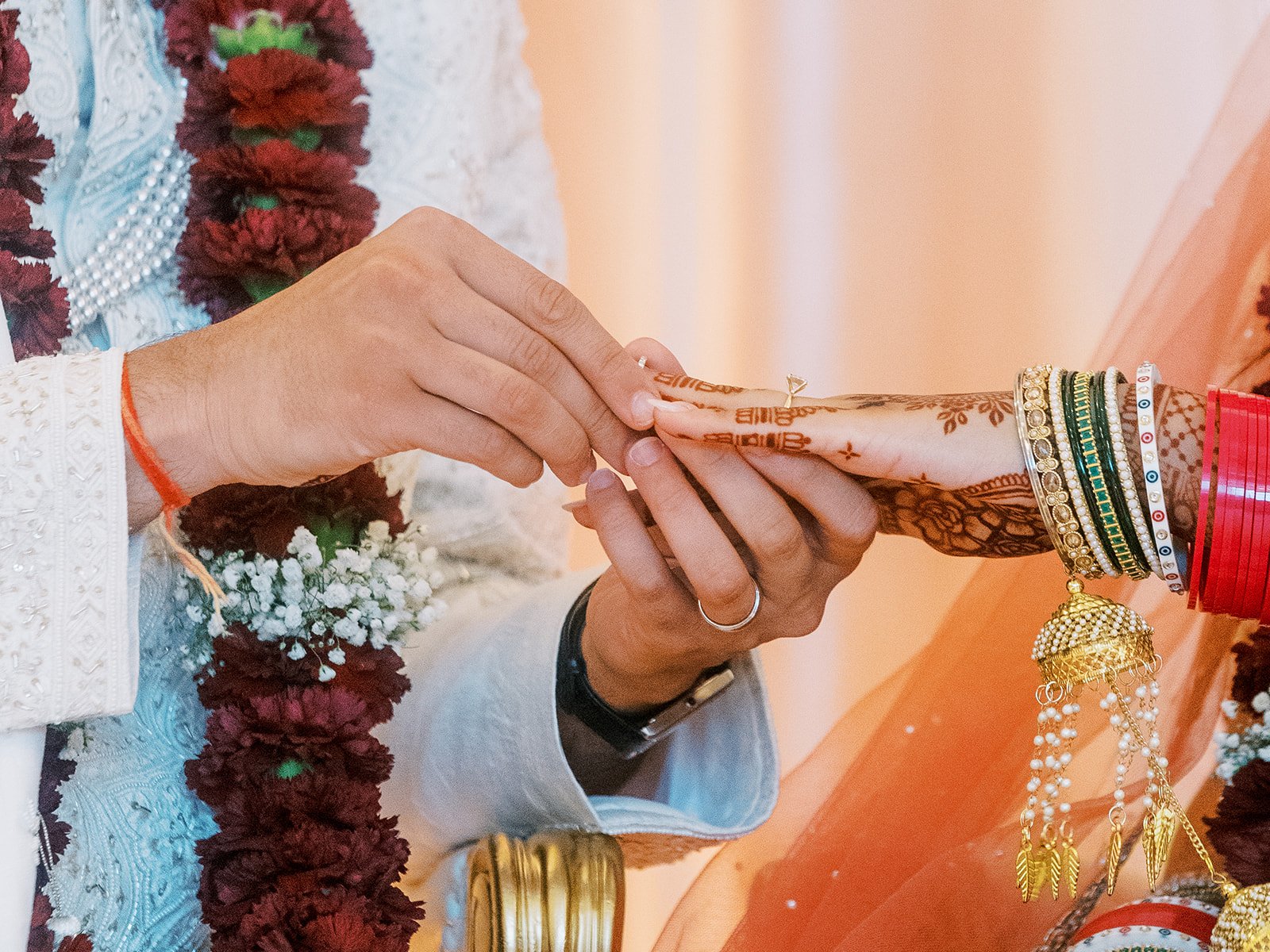 Groom placing diamond ring on bride’s hand during intimate Hindu wedding moment.