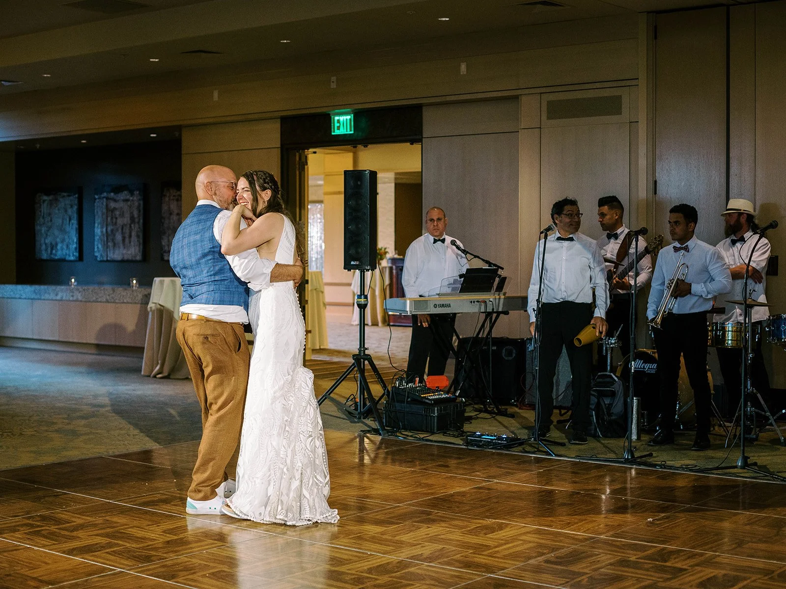 Bride and groom sharing their first dance on the ballroom floor while a live band performs behind them