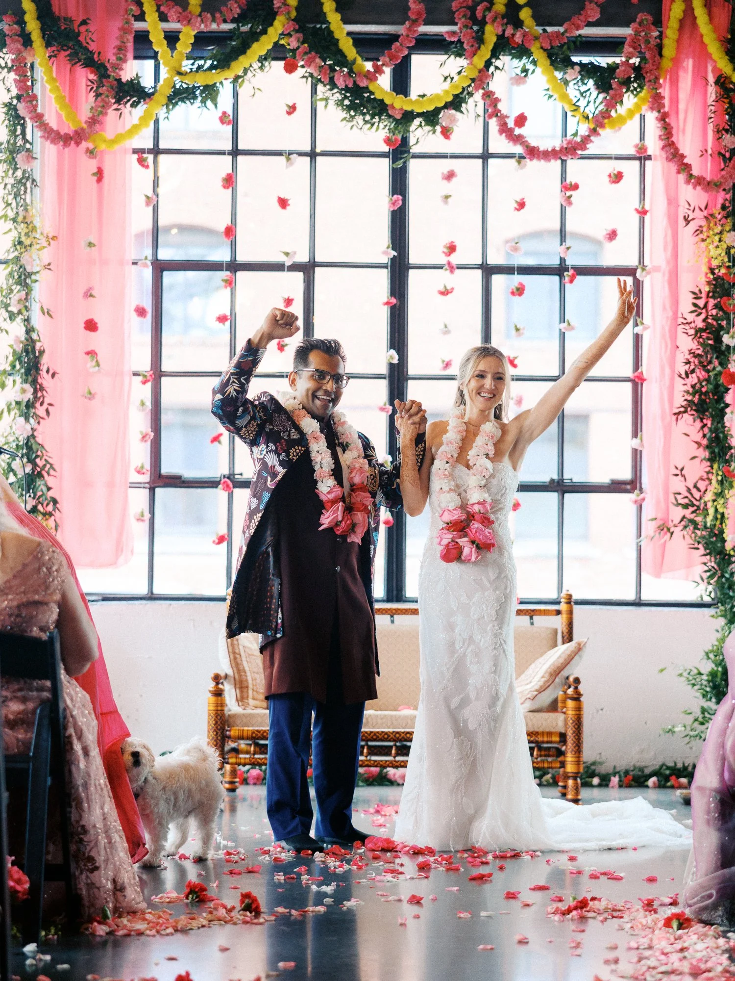 Colorful Castaway Portland wedding ceremony with newlyweds beneath pink and yellow floral garlands.