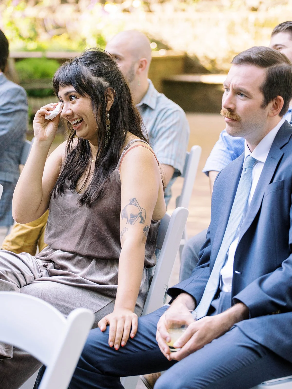 Wedding guest wipes her eye while seated beside another guest during the ceremony.