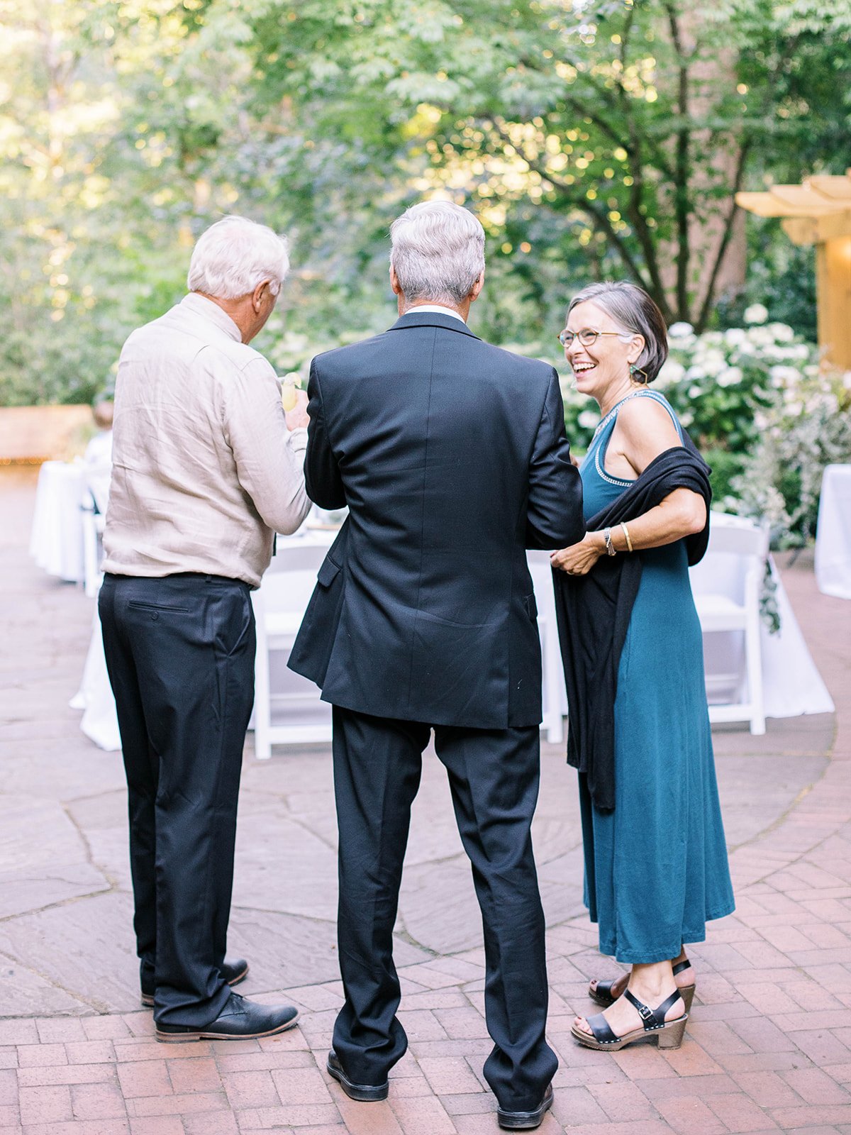 Wedding guests talk and laugh together during the outdoor cocktail hour.