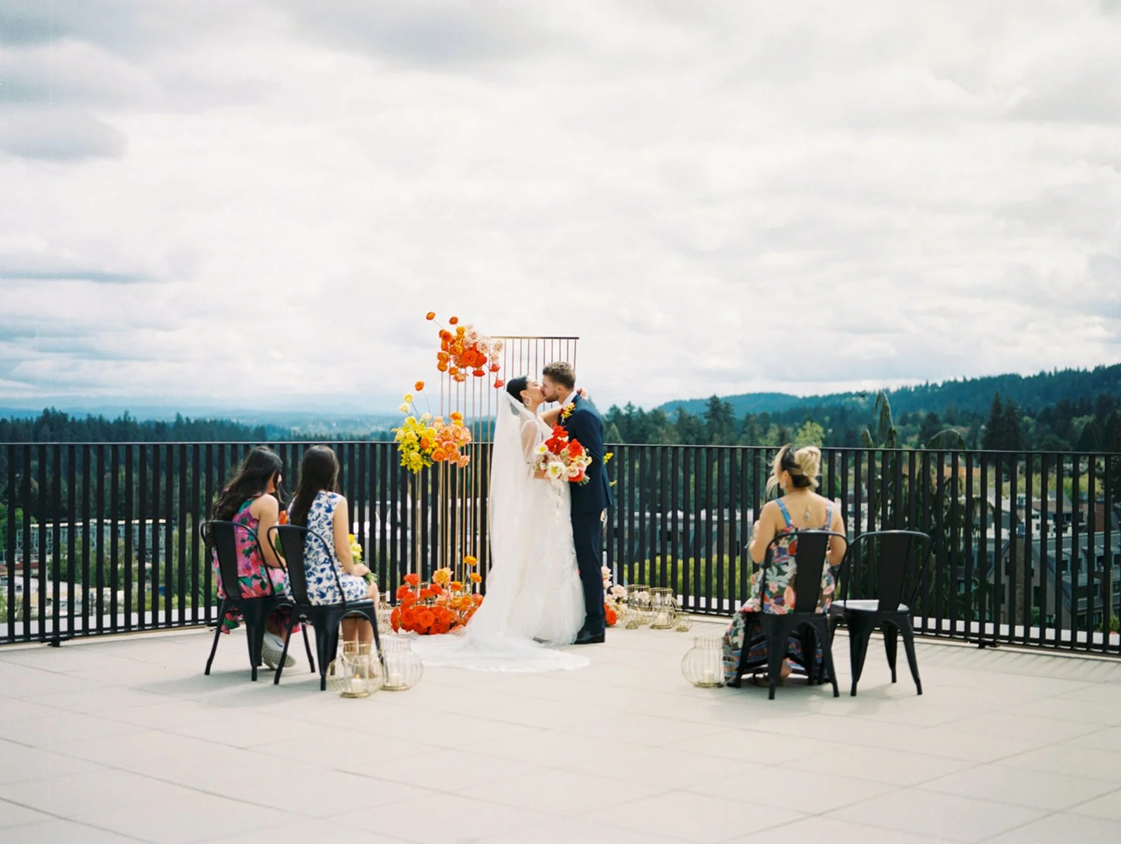Rooftop wedding ceremony at Ironlight with couple kissing under floral installation overlooking scenic landscape