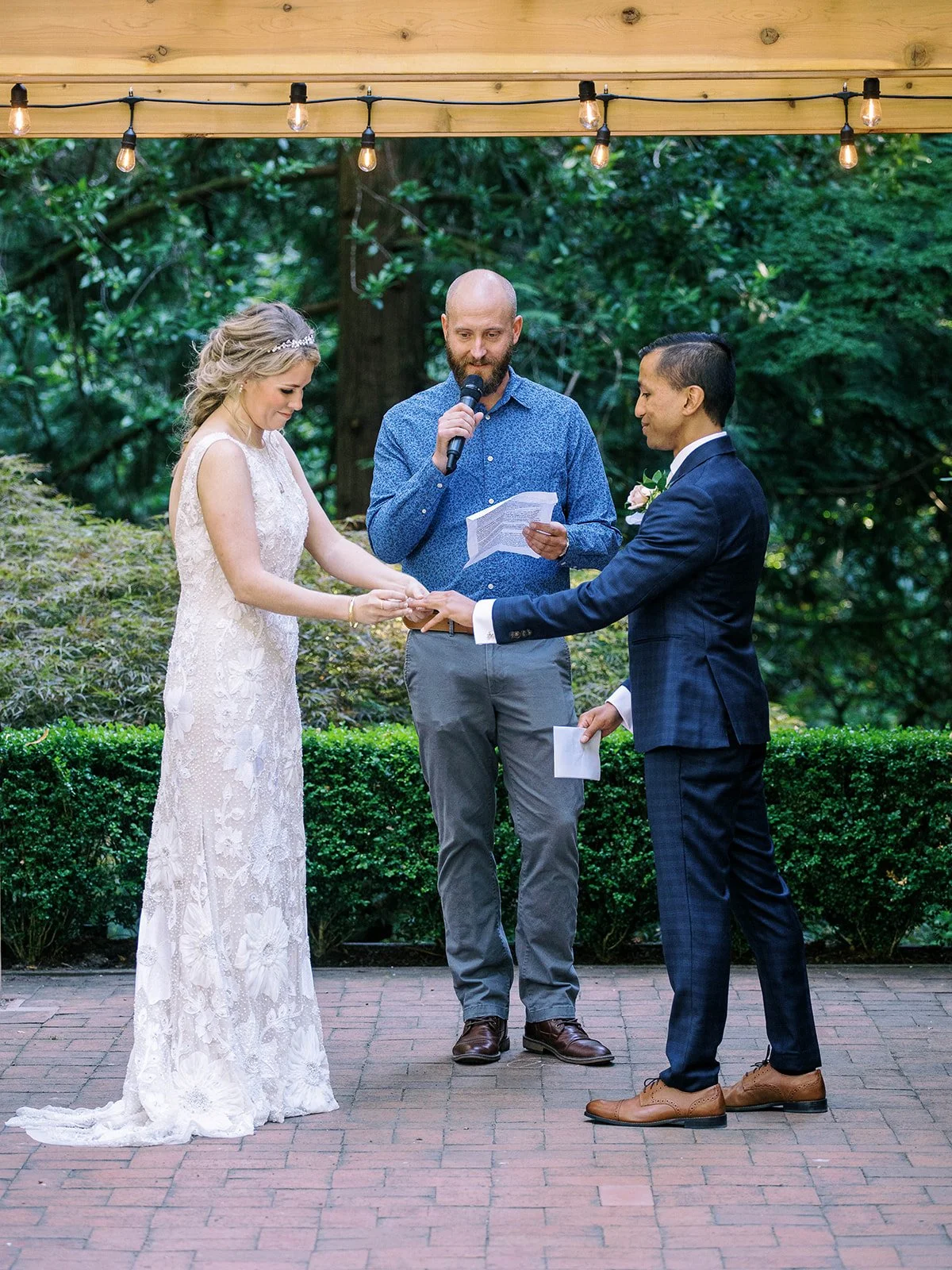 Bride and groom hold hands during their outdoor garden wedding ceremony.