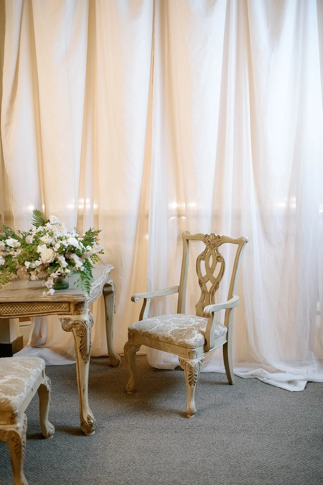 Vintage chair and table with white floral arrangement in the bride’s getting-ready room.