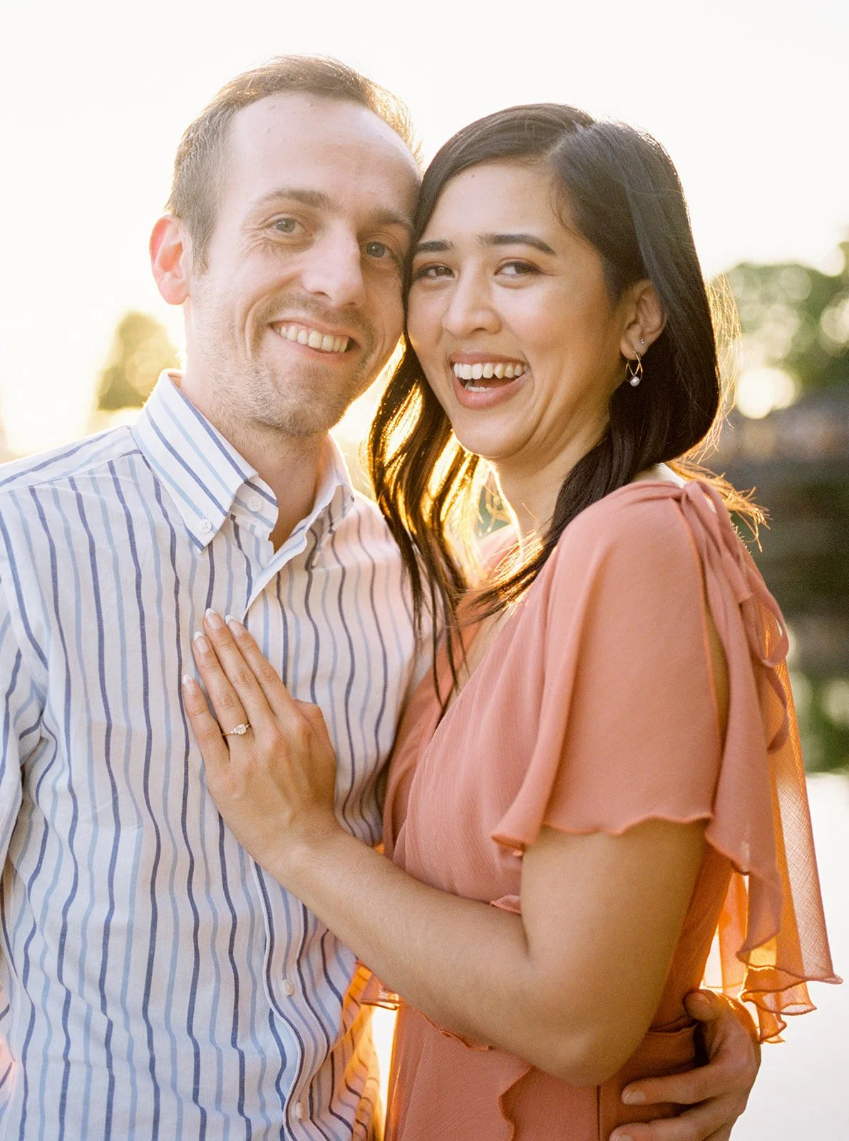 Couple smiling close together at sunset by the lake, warm light highlighting their faces in Oregon