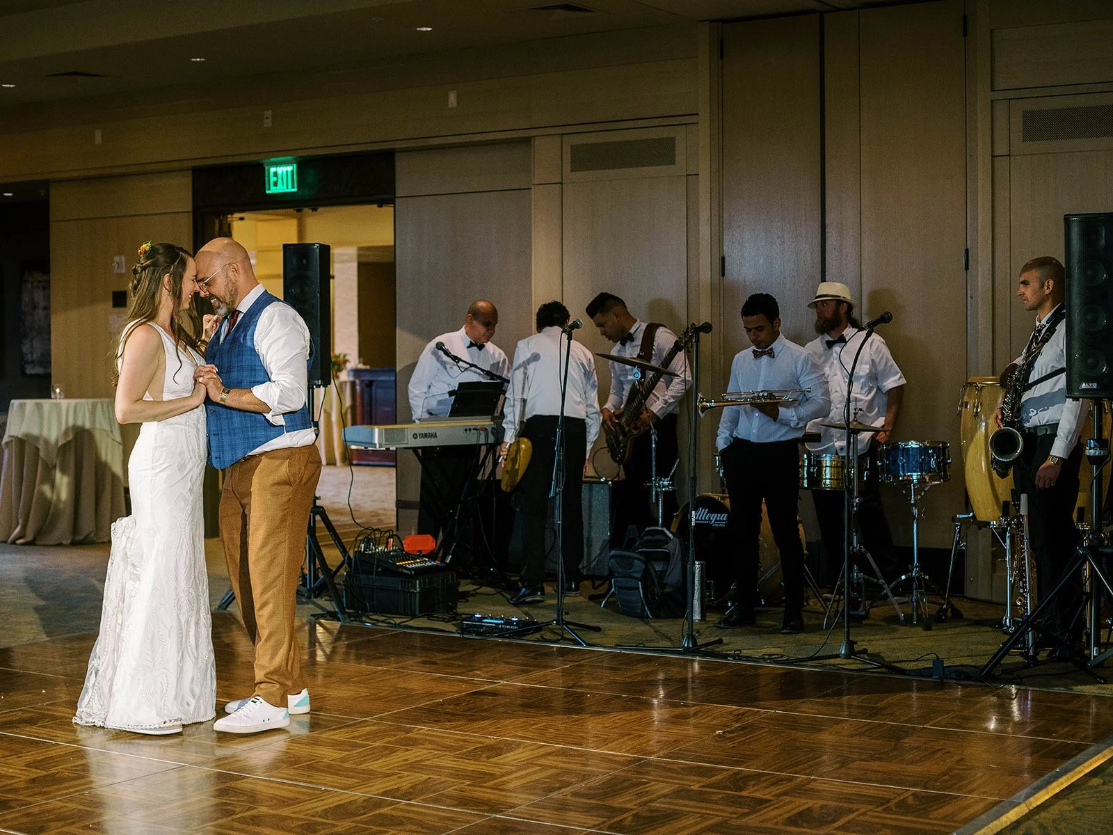 Wide shot of the couple's intimate first dance on the ballroom floor with the full live band setup behind them
