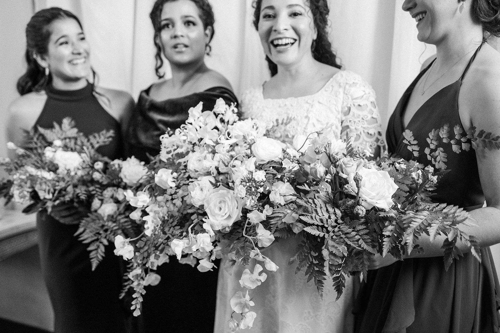 Black-and-white portrait of the bride and attendants gathered with cascading floral bouquets.