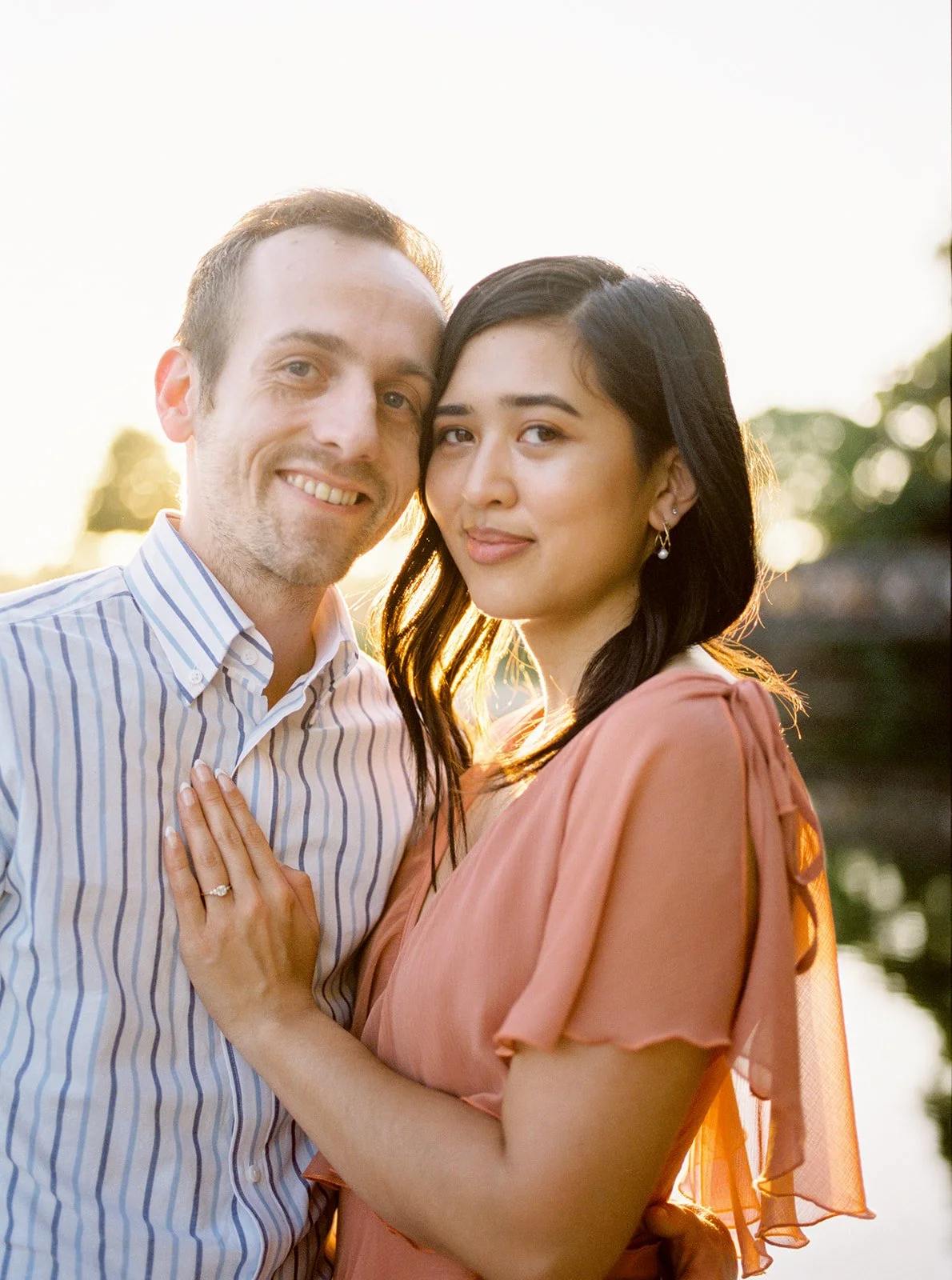 Couple embracing by a lake at sunset, soft golden light behind them during Oregon engagement photos