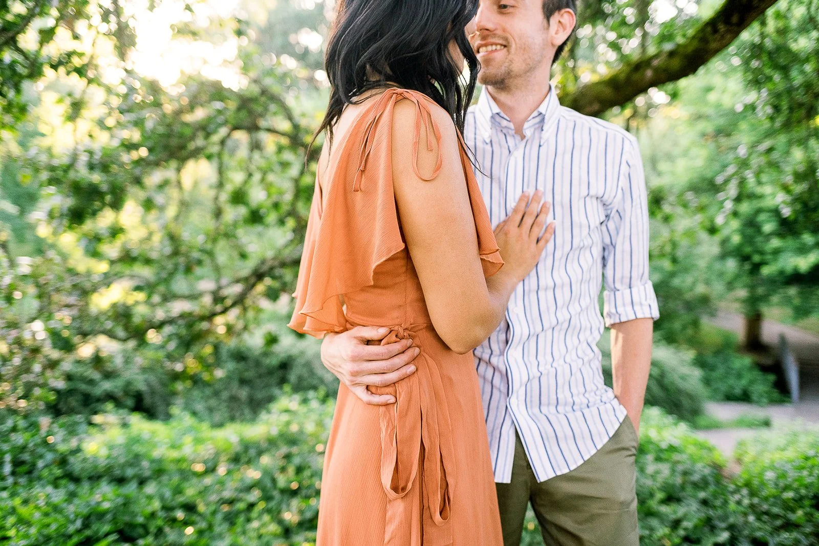 Intimate close-up of couple with engagement ring visible, sunset lake setting in Oregon