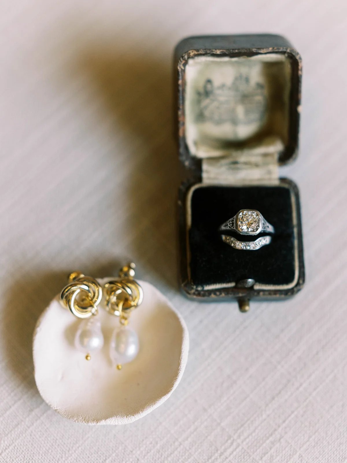 Vintage engagement ring in an open box with pearl drop earrings on a dish, styled wedding details at Oregon Gardens.