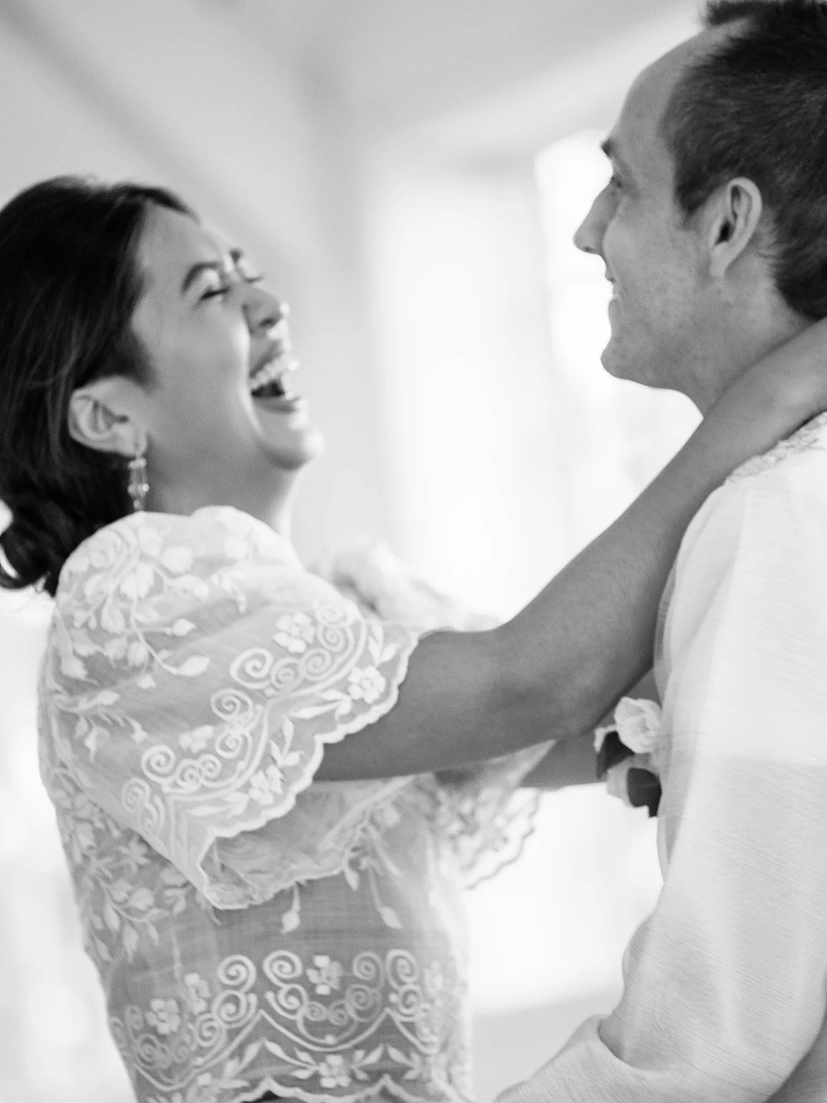 Black and white close-up of the bride laughing with pure joy while dancing with the groom during the reception
