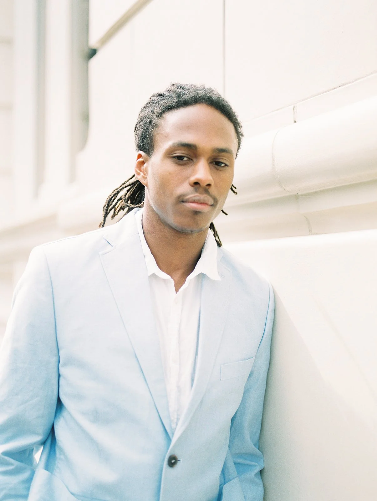 Man in light blue blazer leaning against wall in Portland, casual portrait