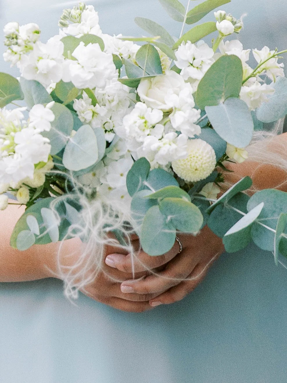 White and eucalyptus bridesmaid bouquet with delicate garden flowers and soft blue dress.