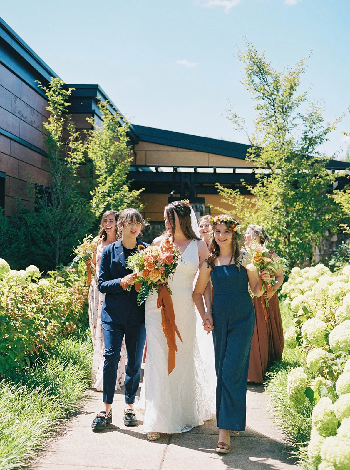 Wedding party walking down garden path with bride holding bouquet at center