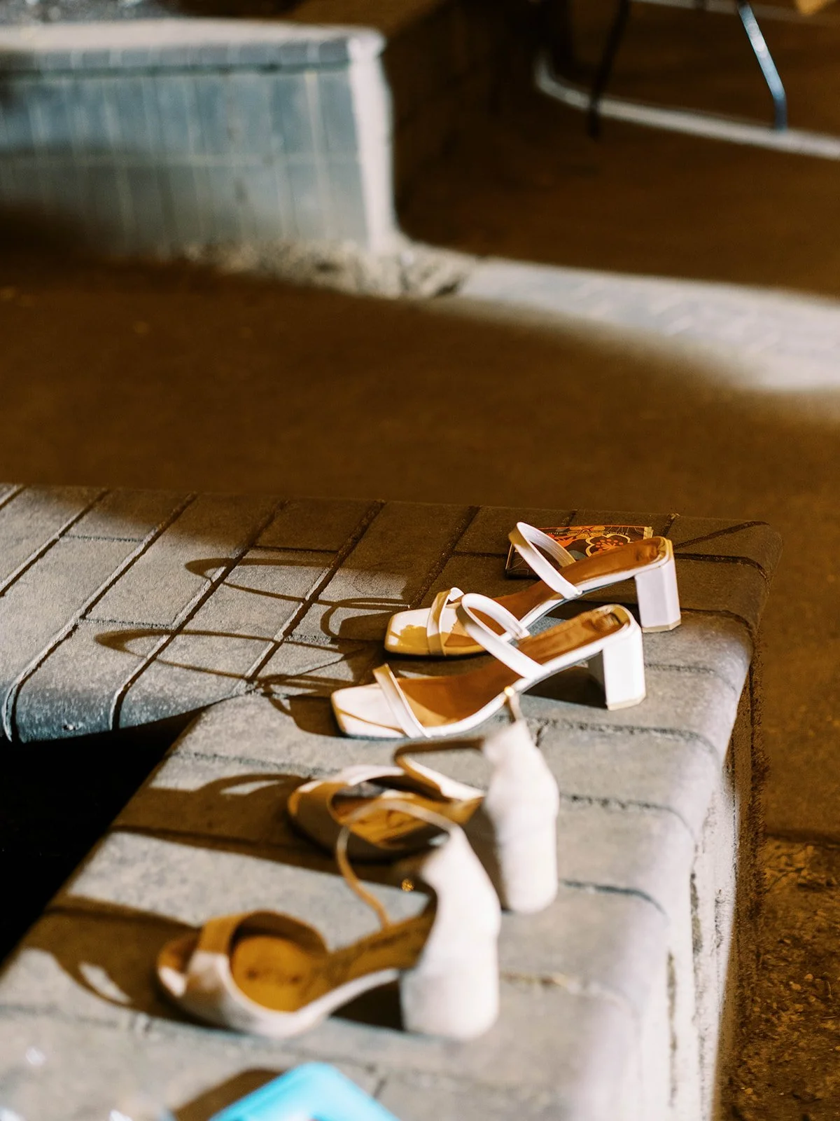 White heeled sandals placed on stone ledge during nighttime wedding reception