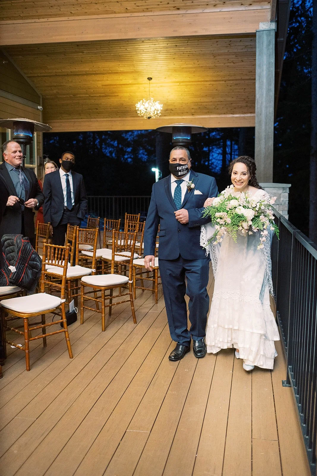 Bride carrying a cascading bouquet walks down the aisle with her father during an Oregon wedding.
