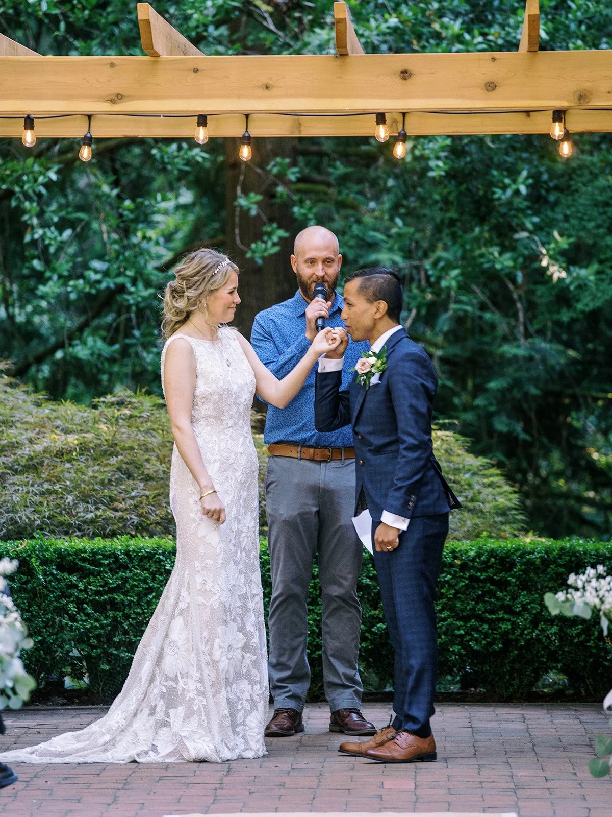 Groom kisses the bride’s hand during their outdoor wedding ceremony.