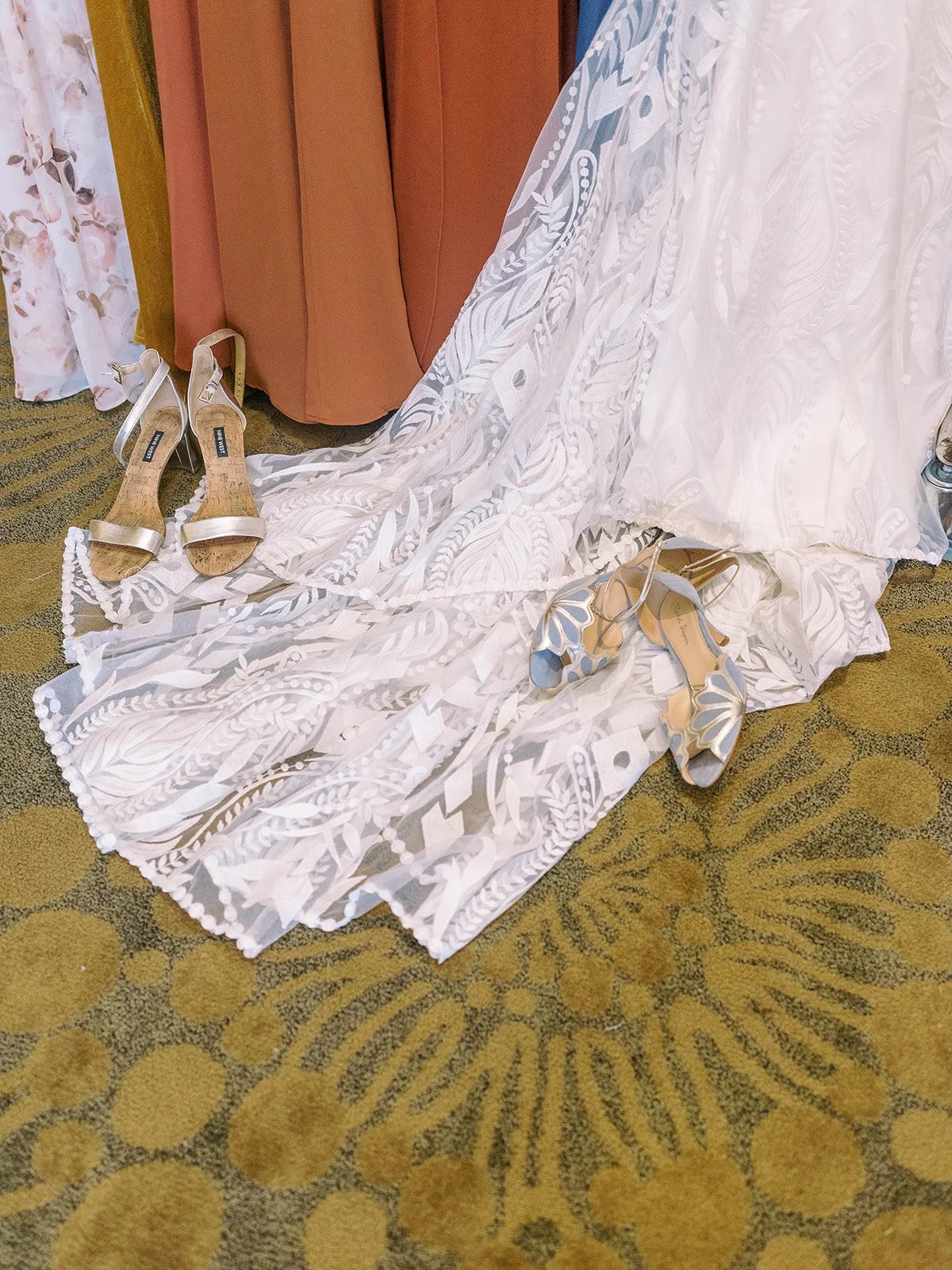 Lace wedding dress with blue bridal shoes and gold heels arranged on patterned carpet