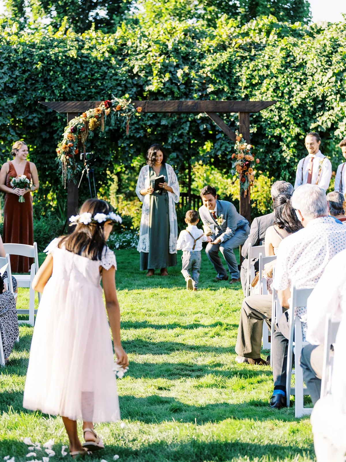 Wedding ceremony in garden, guests seated as couple prepares to begin