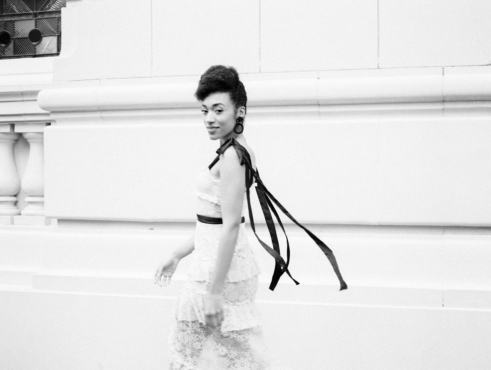 Woman in pink dress walking along Portland sidewalk with flowing black ribbon details