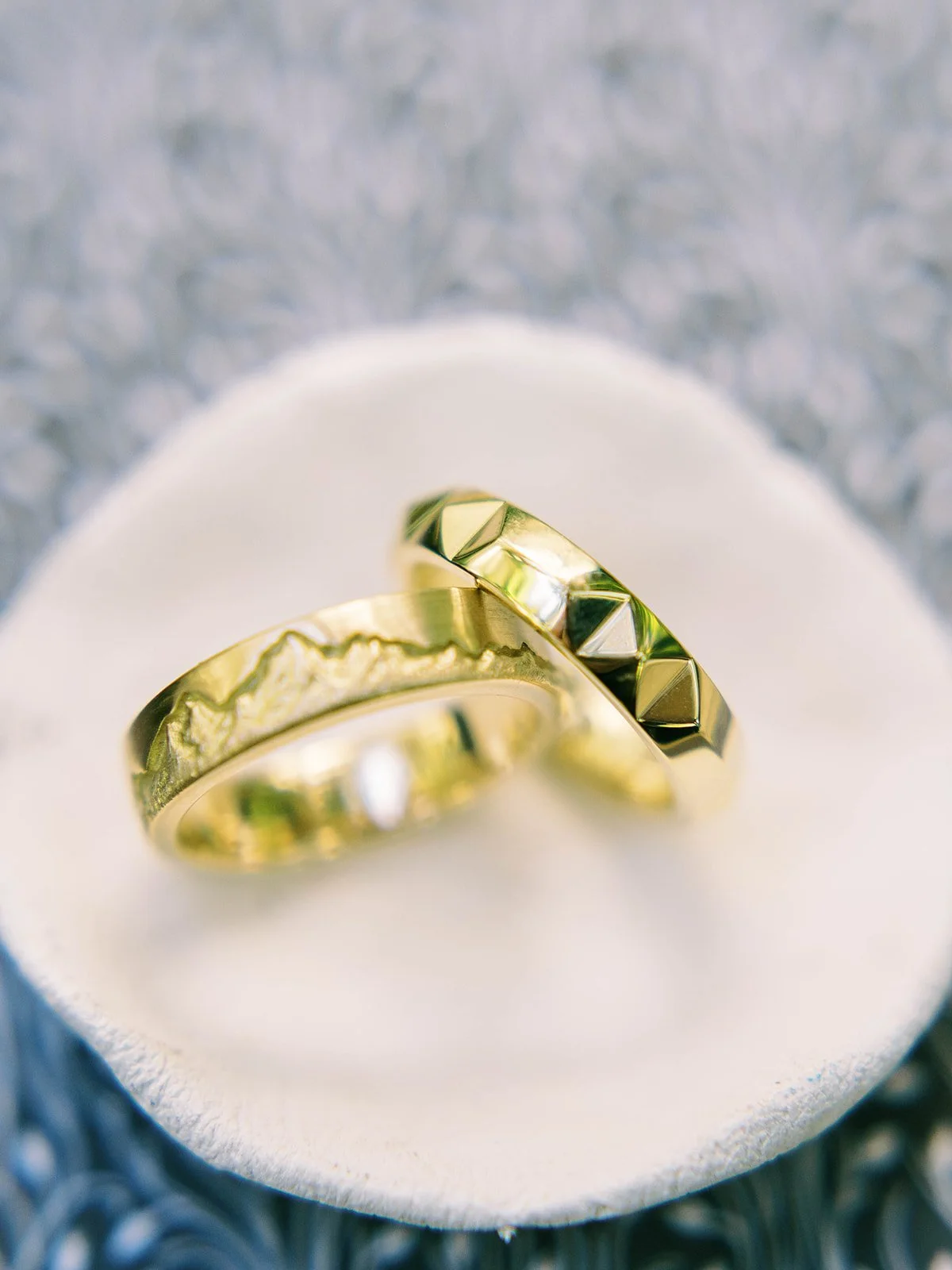 Custom gold wedding bands with mountain and geometric details displayed together.