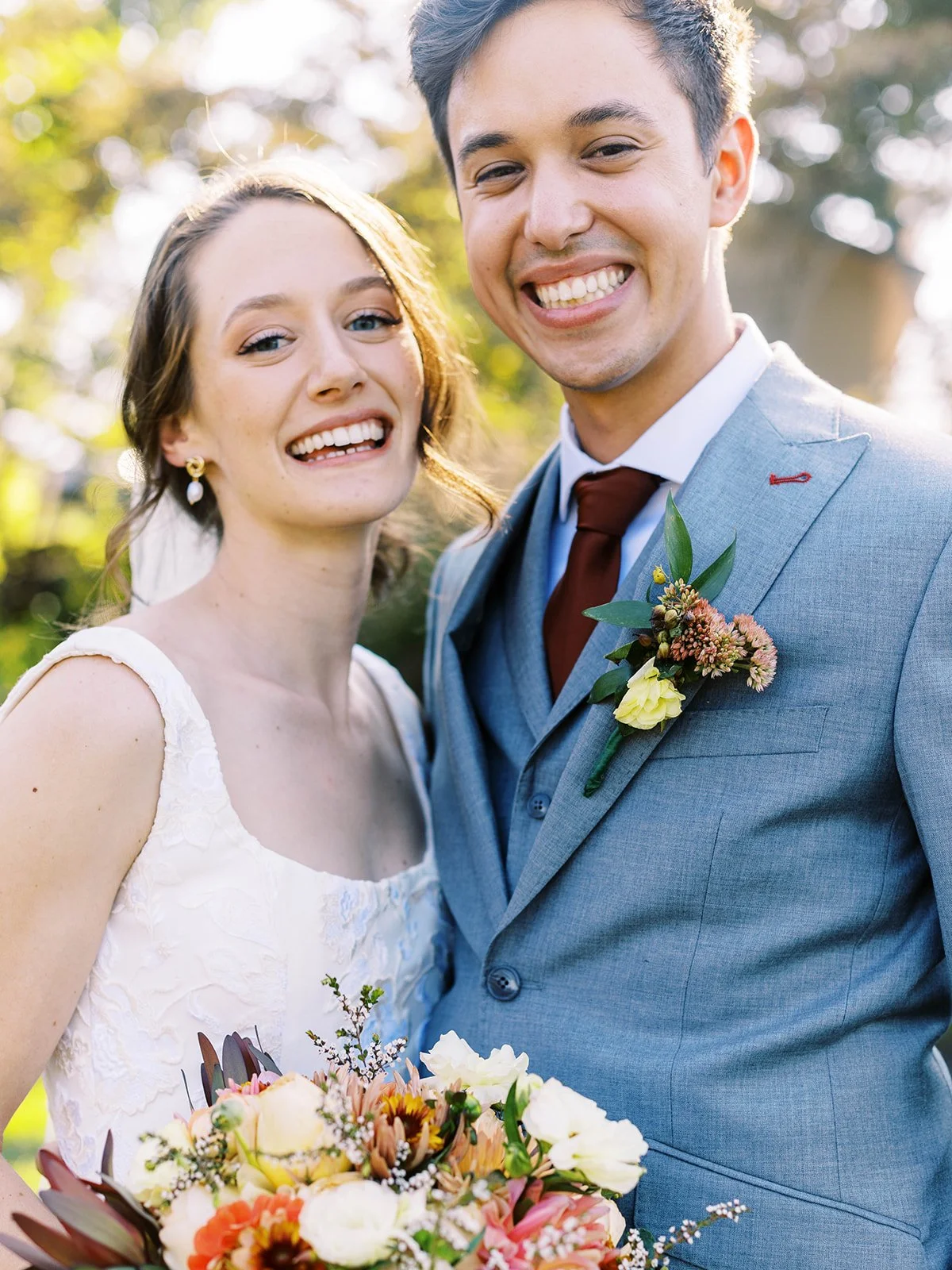 Smiling bride and groom in garden, close-up with colorful bouquet and soft sunlight