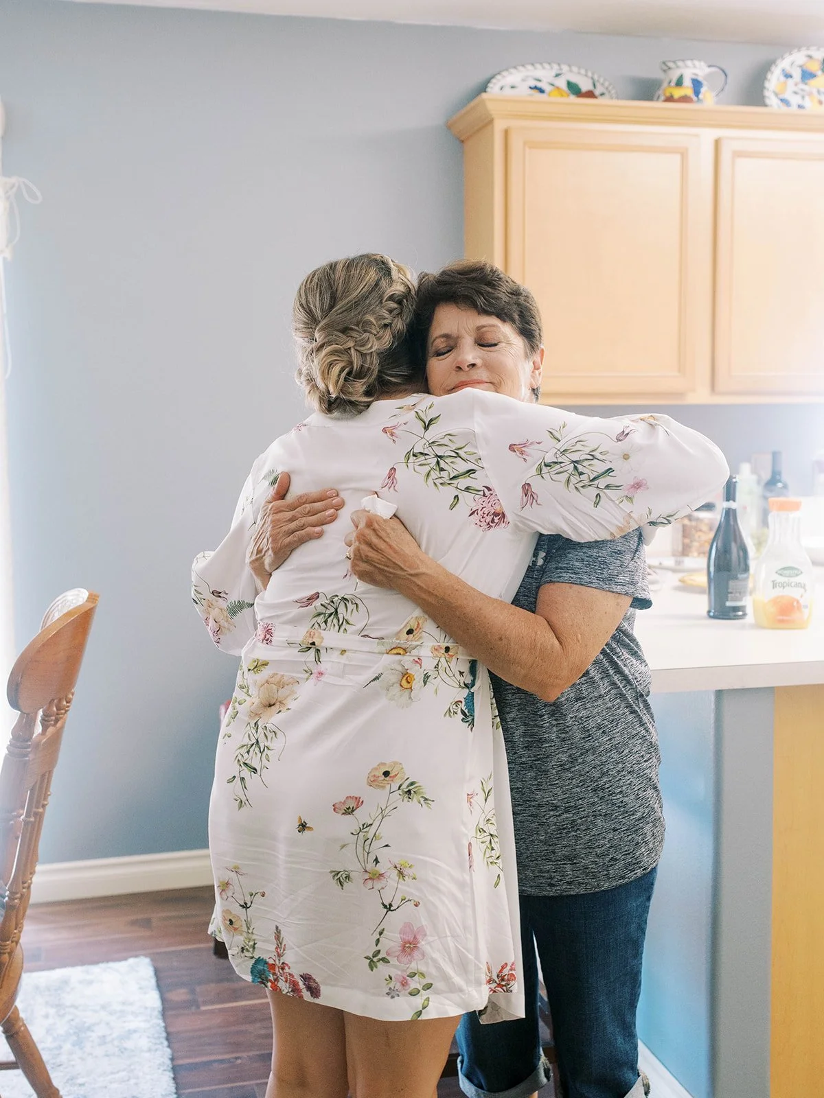Bride hugging her mother in floral robe during emotional wedding morning preparations at Abernathy Center.
