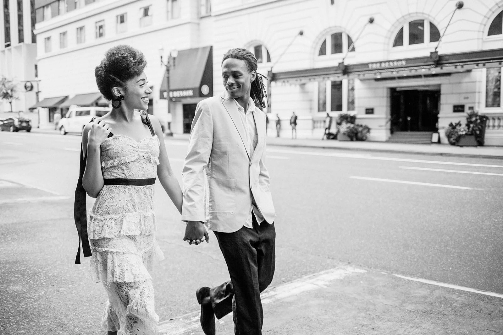 Black and white image of couple walking along downtown Portland street near historic hotel