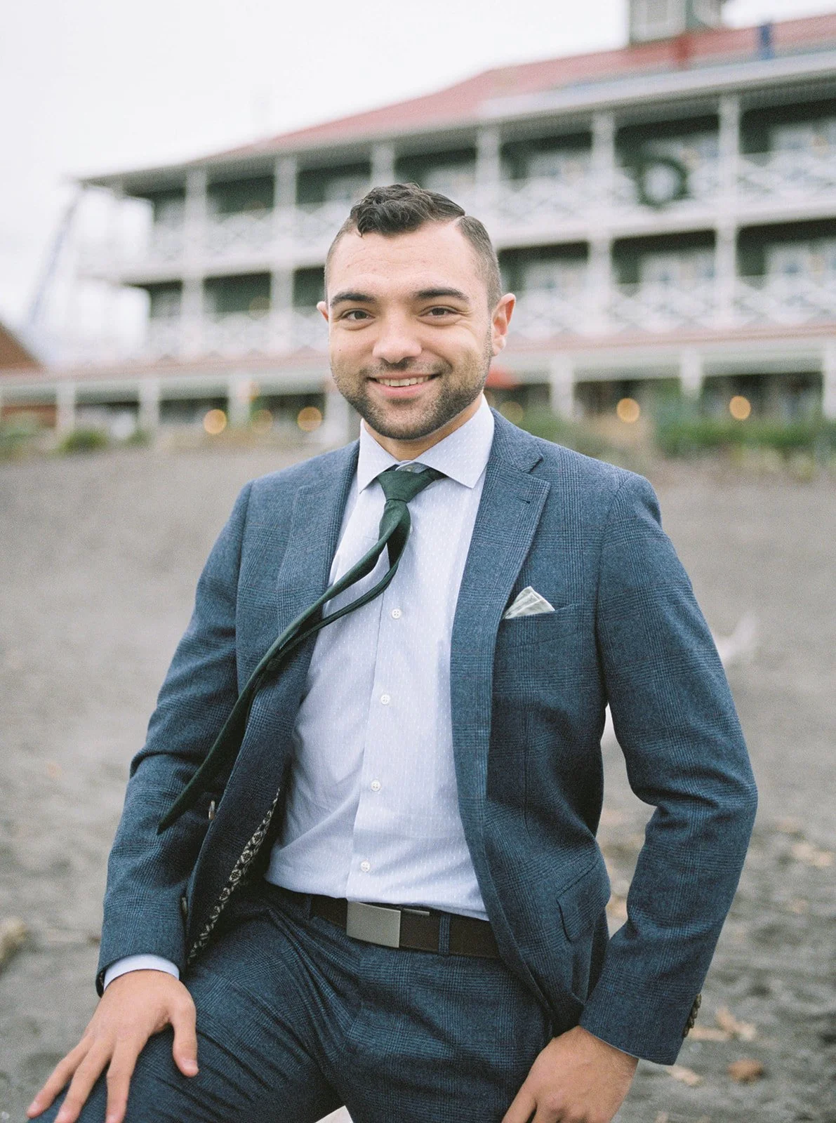 Groom in a blue suit and green tie photographed outdoors during his Oregon wedding day.