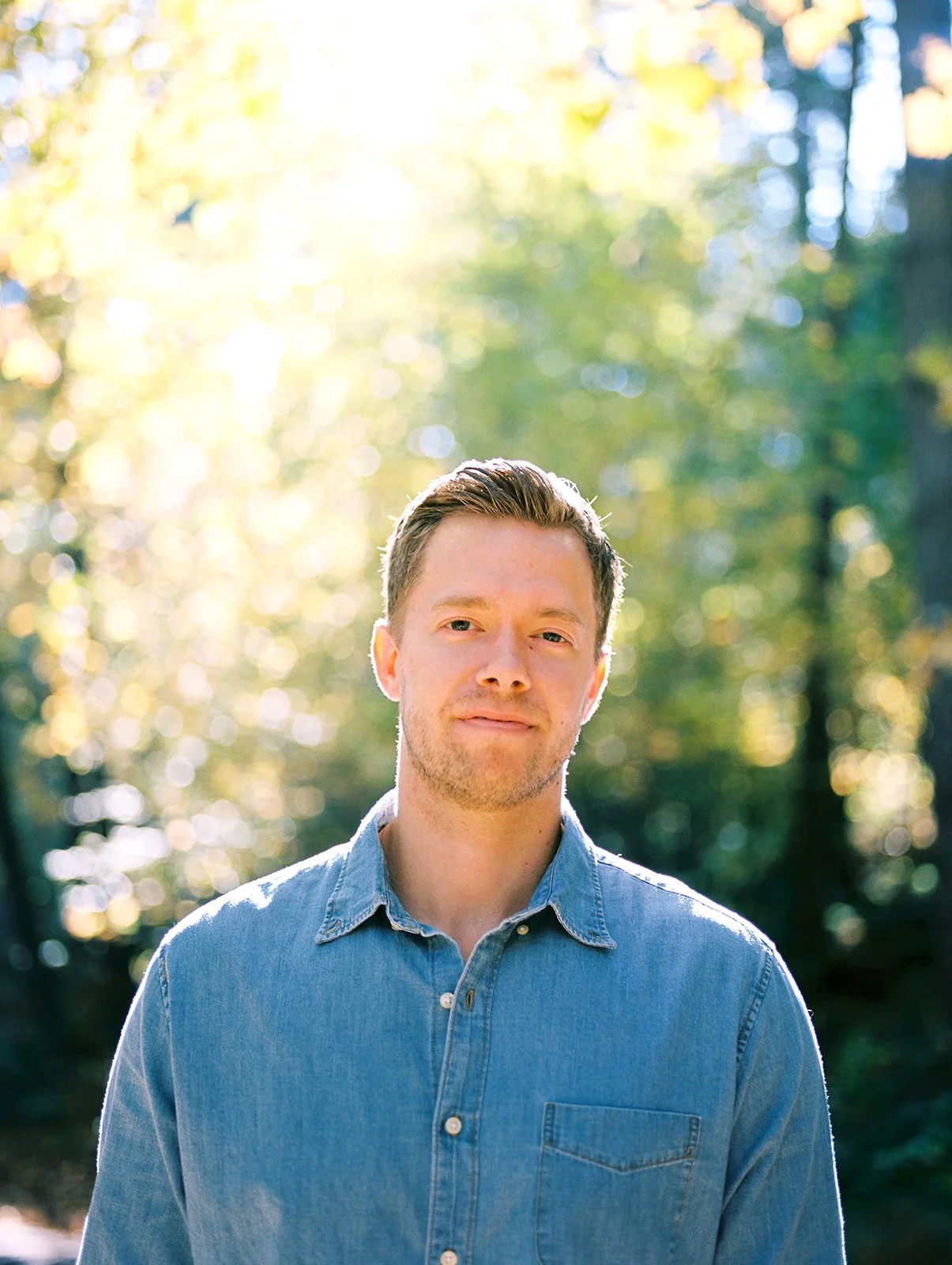 Close-up portrait of man with soft backlight and autumn foliage in forest setting