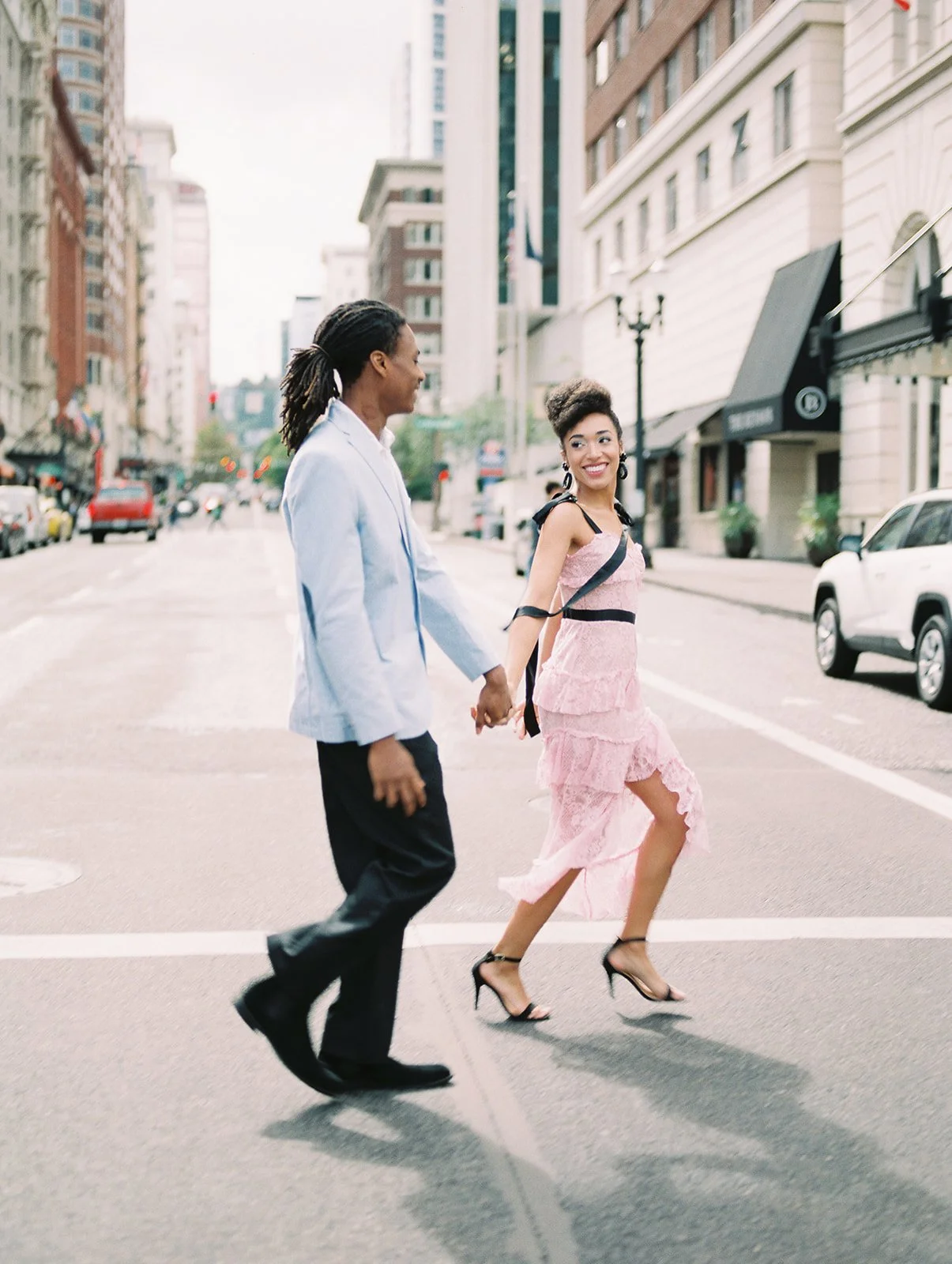 Couple crossing street together in downtown Portland, woman in pink dress and black heels