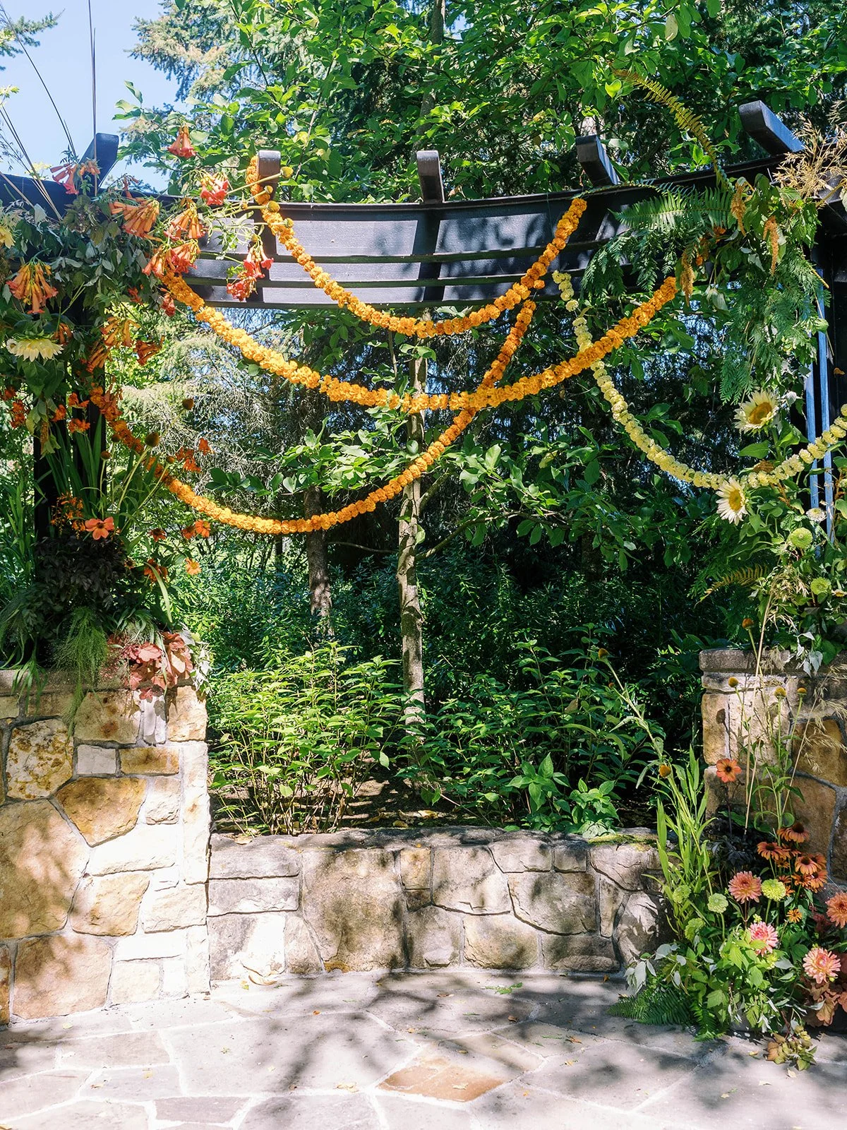 Outdoor wedding ceremony arbor decorated with marigold garlands and greenery at The Allison Inn.