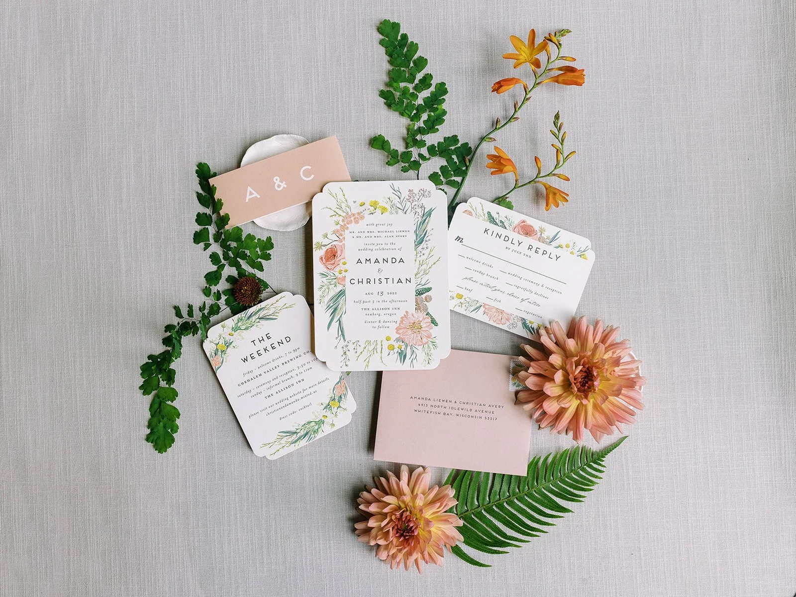 Floral wedding invitation suite with greenery, orange blooms, and peach RSVP cards on linen background