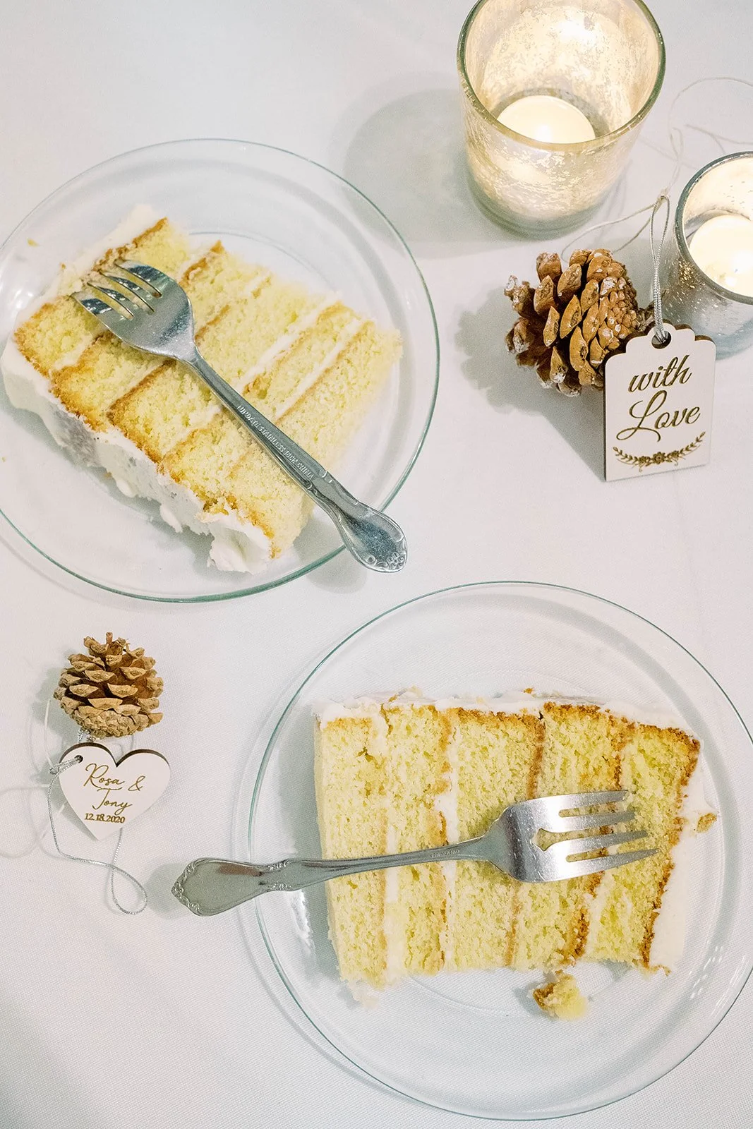 Slices of wedding cake displayed with candles, pinecones, forks, and personalized wedding tags.
