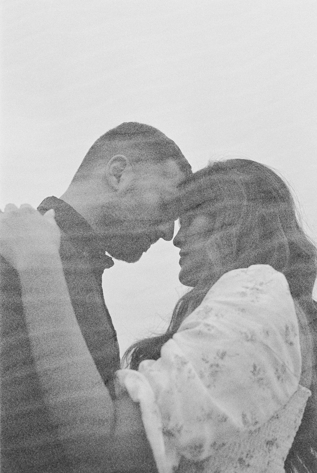 Grainy black and white close-up of couple touching foreheads in intimate moment