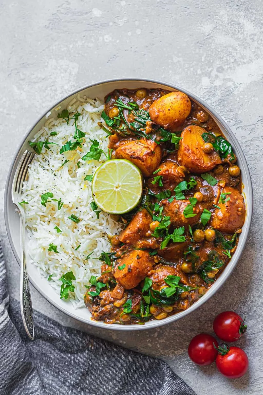 Creamy vegan potato curry with spinach and peas served over rice