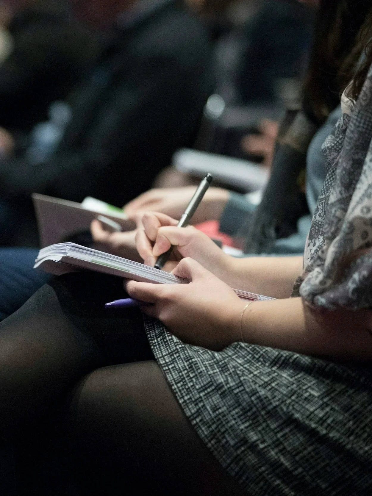Attendees taking notes during a corporate conference session, representing professional event planning services.