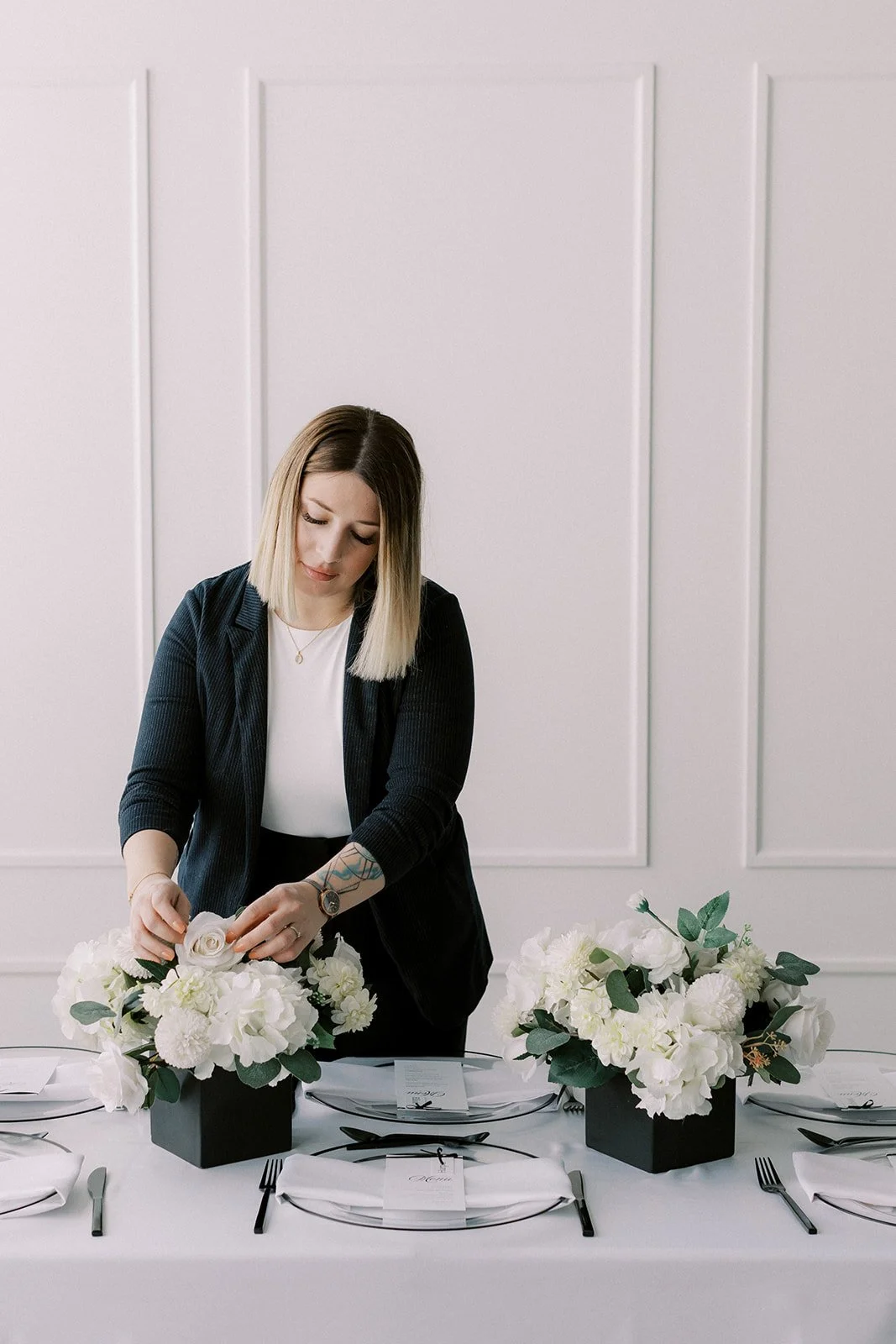 Neesa, Calgary-based event planner, setting up a minimalist black and white table design.
