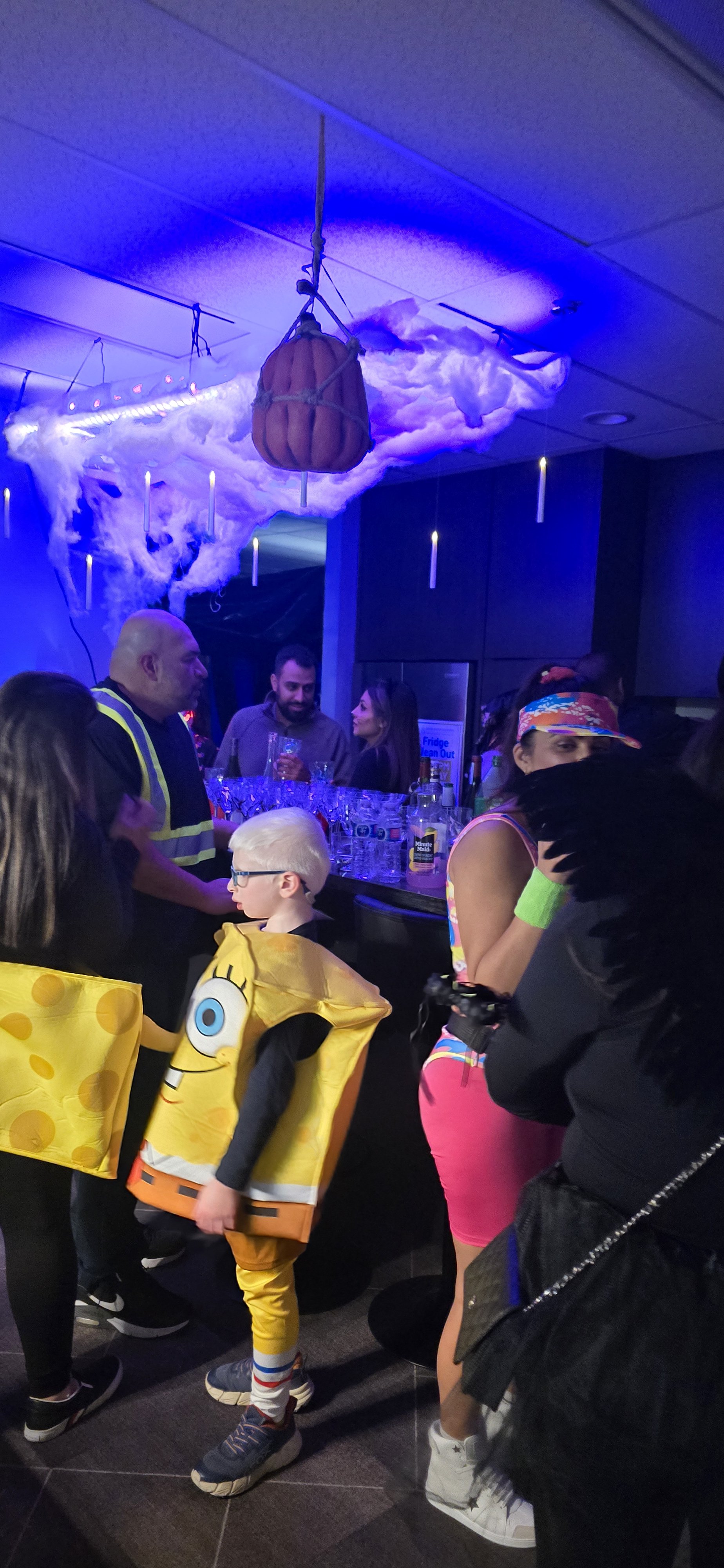 A halloween party with guests in costumes and a dark purple cloud hanging over the bar designed and planned by Neesa and Co Events.