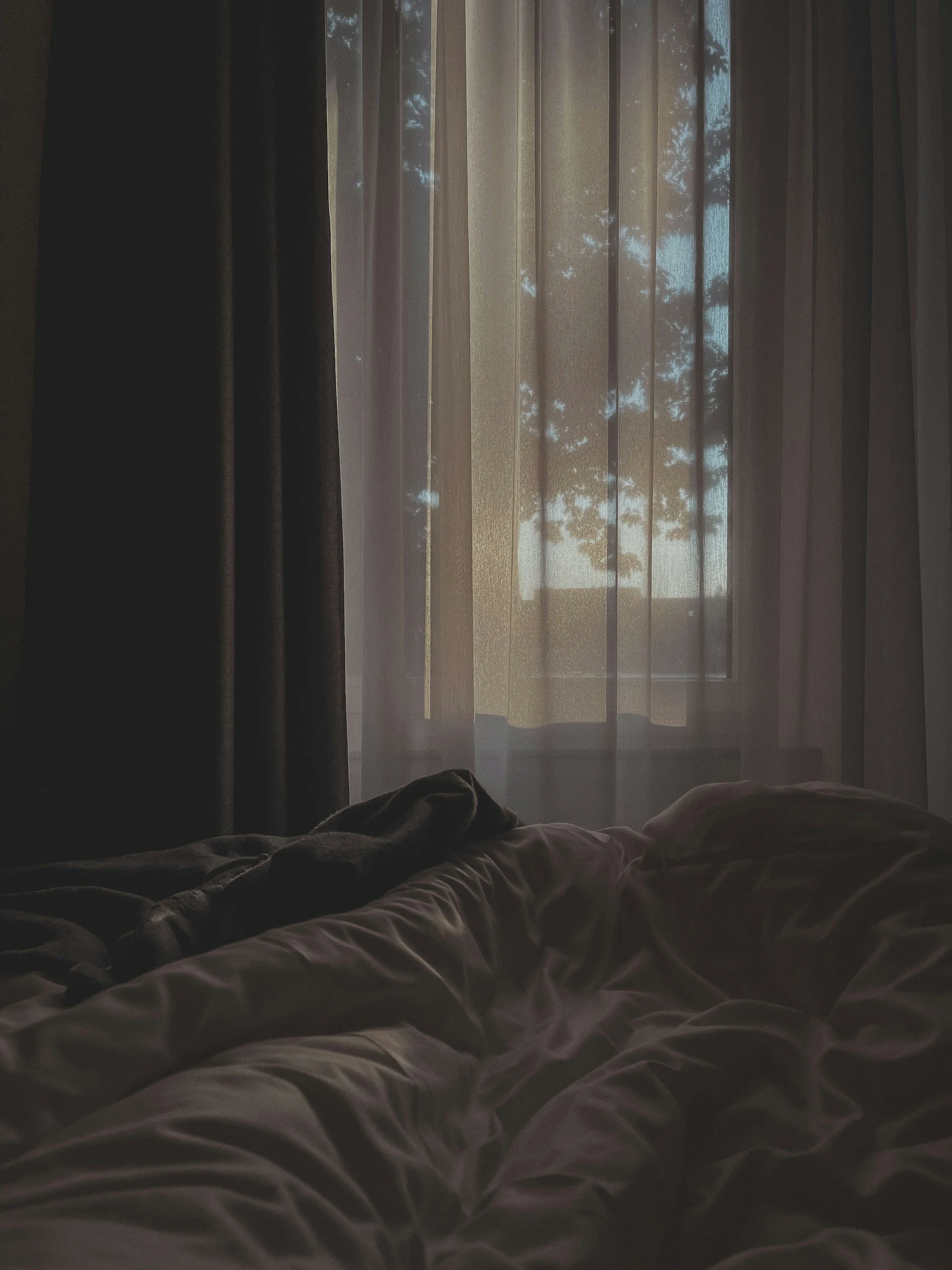 A cozy relaxing bedroom white bedsheets and white linen window curtain
