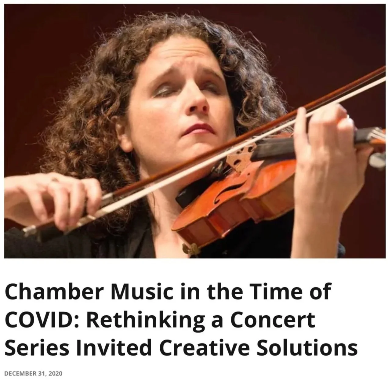 A woman with curly hair playing a violin with her eyes closed, focused on her music.