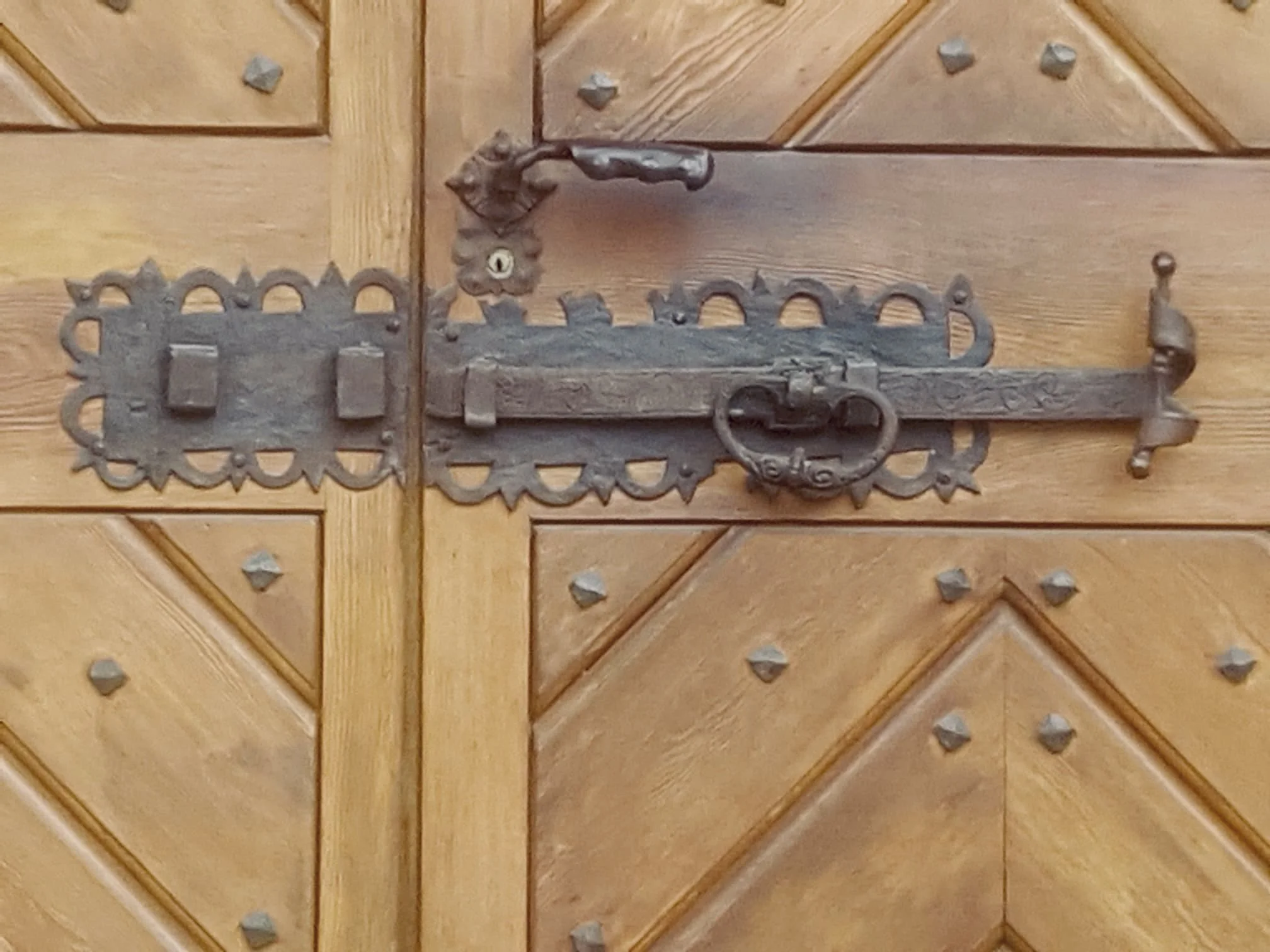 Holztür mit antiker Eisenklinke und Schloss, dekorativen Eisenringen und Mustern.