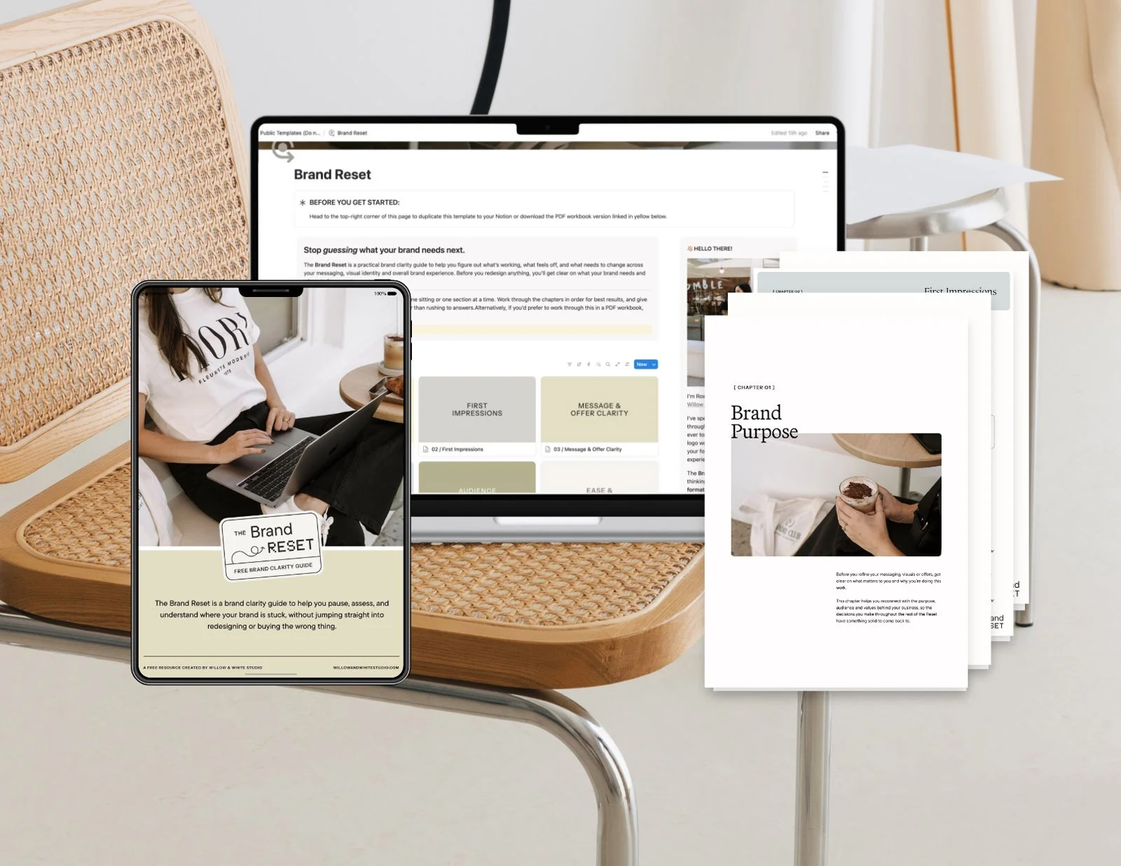 A desk with a laptop, tablet, and printed papers about branding and brand clarity, with a woman in a white shirt working on her laptop, in a modern and minimalist setting.