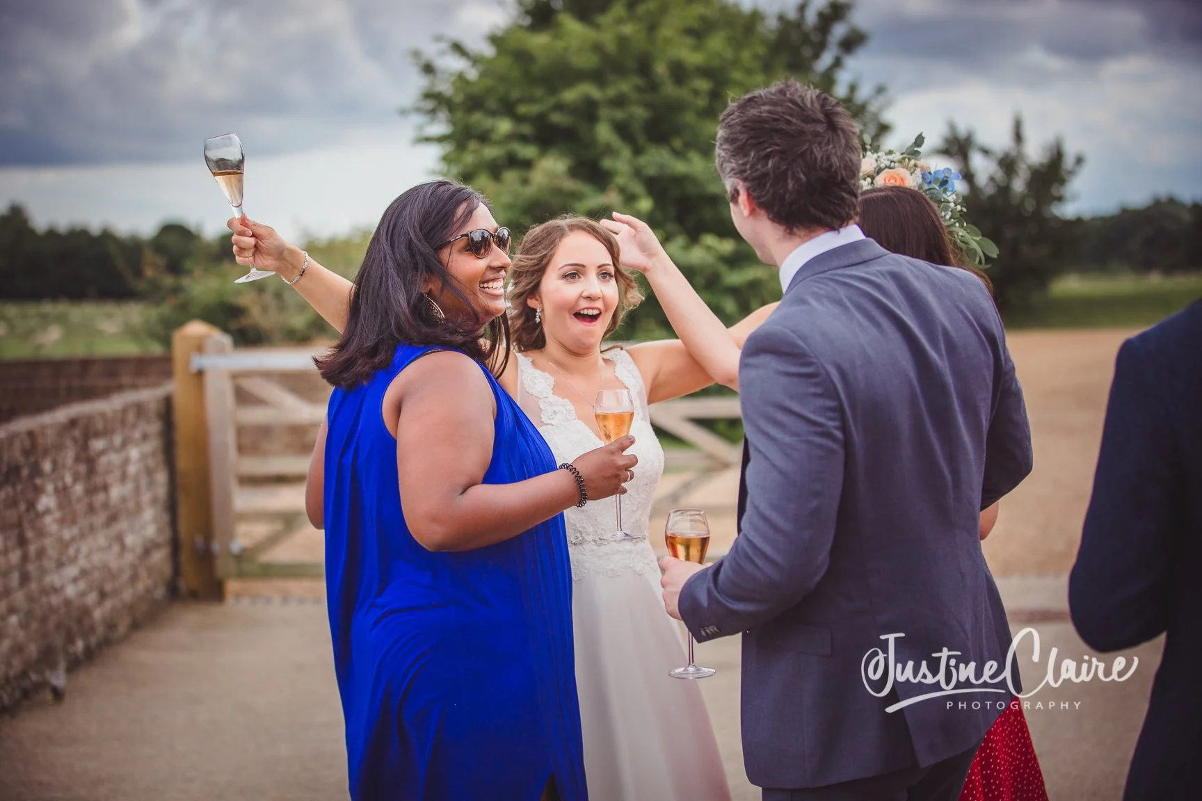 People celebrating outdoors at a wedding with drinks in hand, smiling and interacting.