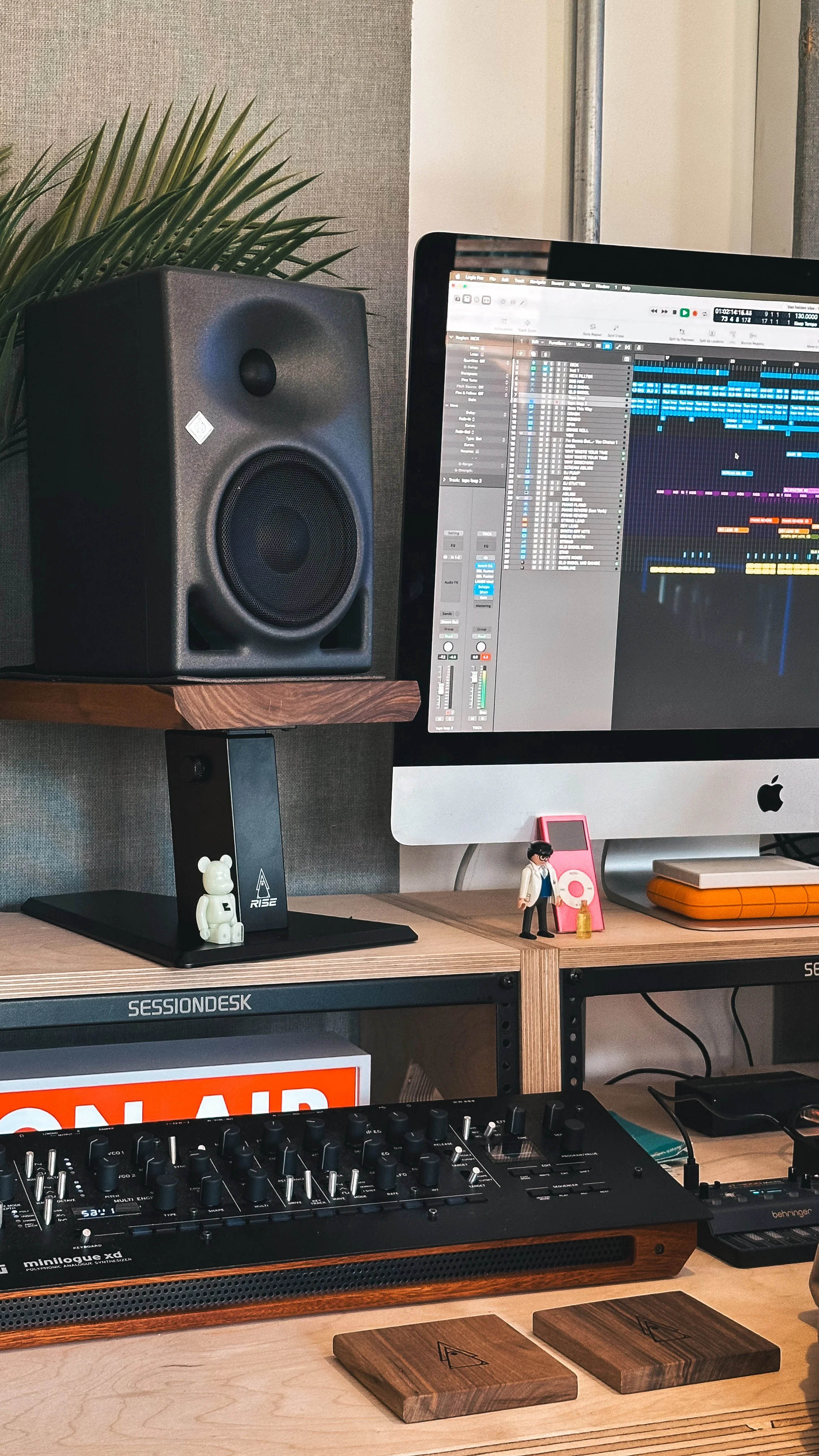 Close-up of a black studio speaker resting on a solid walnut monitor stand platform