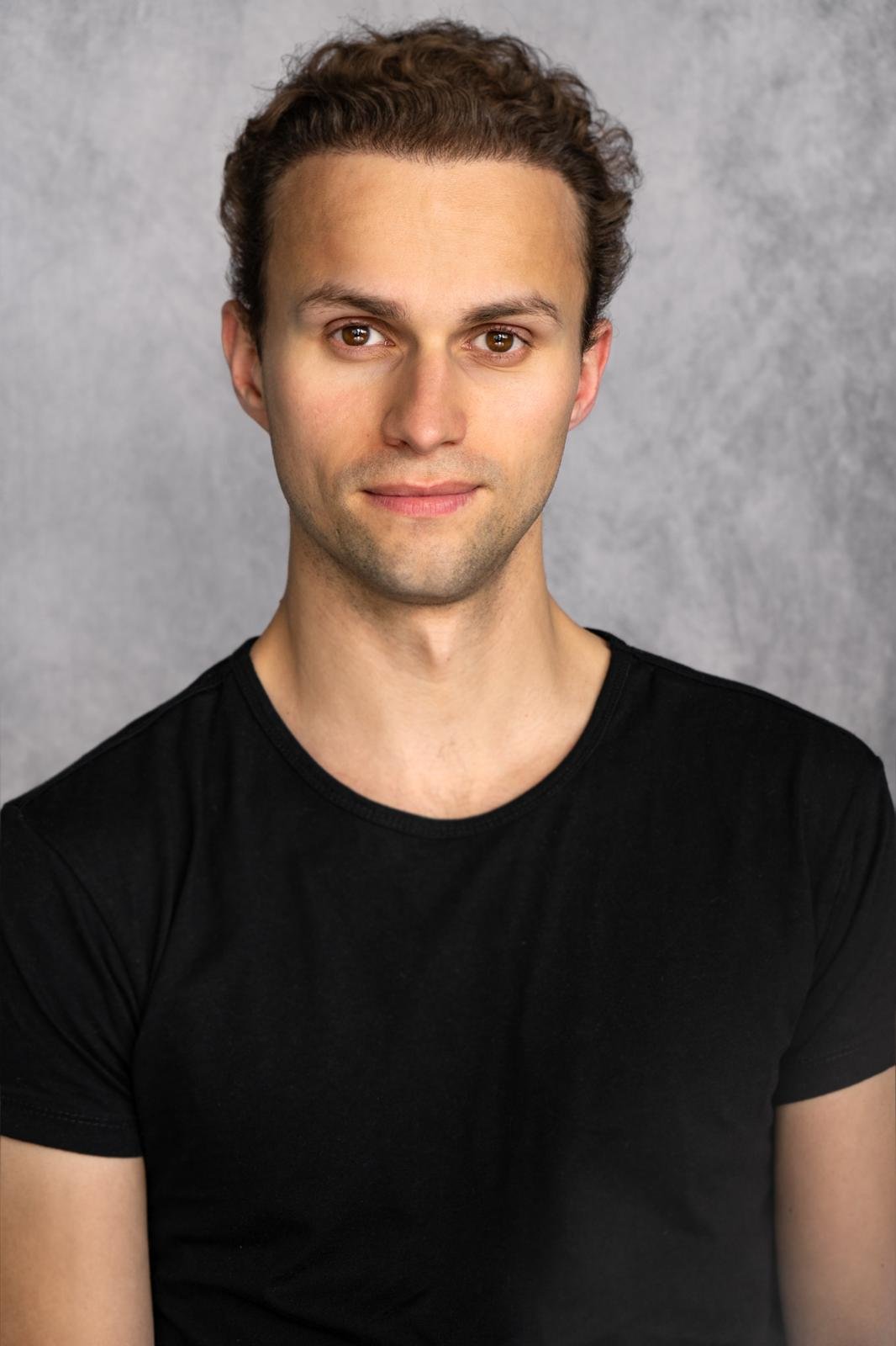 Lachende jonge man voor een gekleurde graffiti-muur.