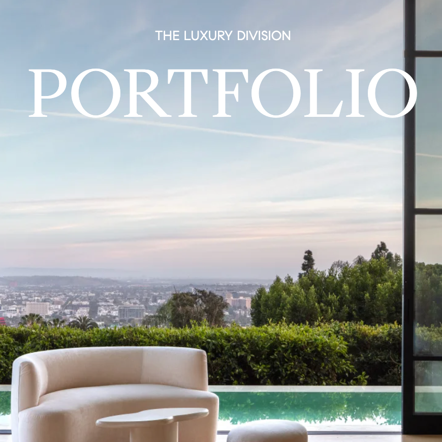 Cover of a luxury portfolio magazine featuring a modern outdoor seating area with a white curved sofa and small white table, overlooking a city skyline with trees and a pool, under a blue sky.